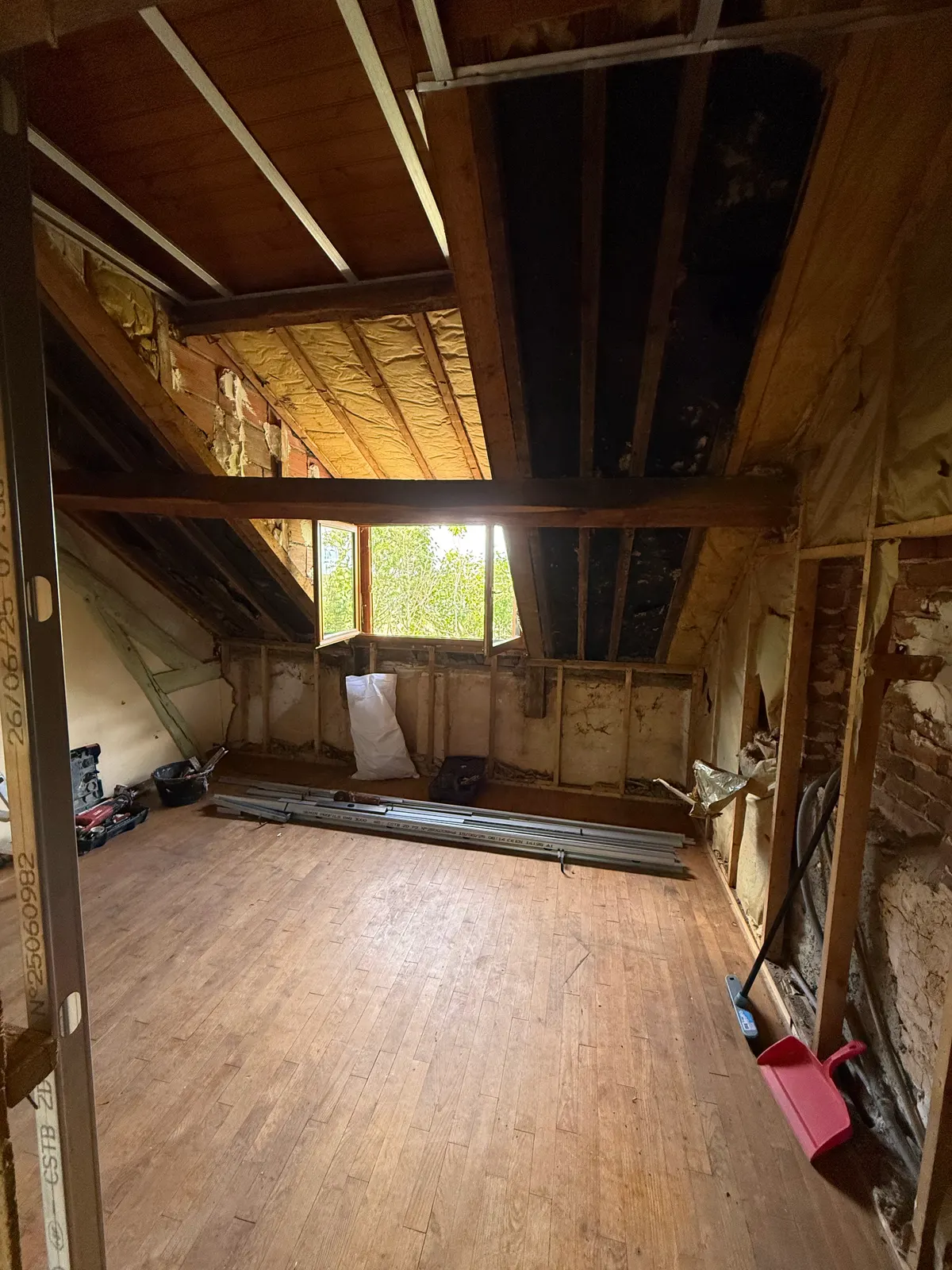 Comble avant travaux : charpente apparente, ancienne isolation et murs en brique